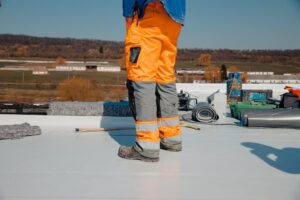 Roofer working on top of flat roof building 