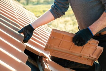 Roofing professional performing repair services for tile roof